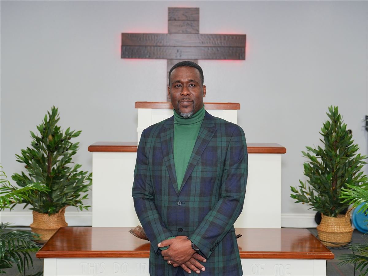 Pastor Dennis Libert standing before the cross at Deliverance Baptist Church in Marianna, Florida
